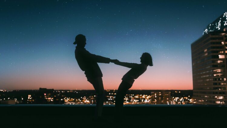 A silhouette of a couple under a starry sky with heart-shaped constellations, designed as a Love and Relationships Manifestation Wallpaper, symbolizing love and connection.